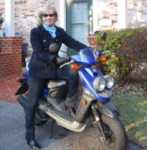 Alice McKenna on blue scooter in front of house