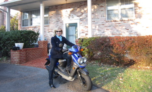 Alice McKenna on blue scooter in front of house