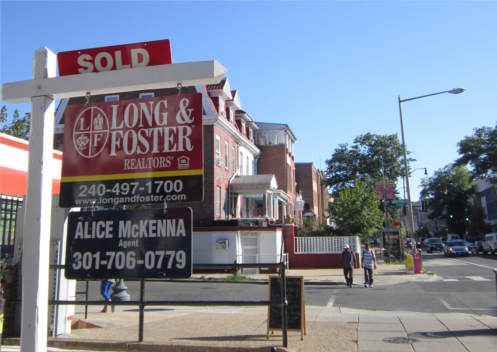 Sold sign against blue sky, streetscape